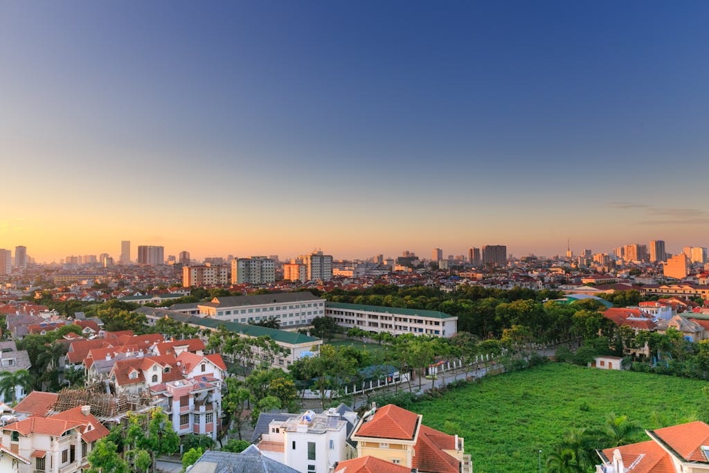 Aerial view of a vibrant cityscape with lush greenery and architecture at sunset.